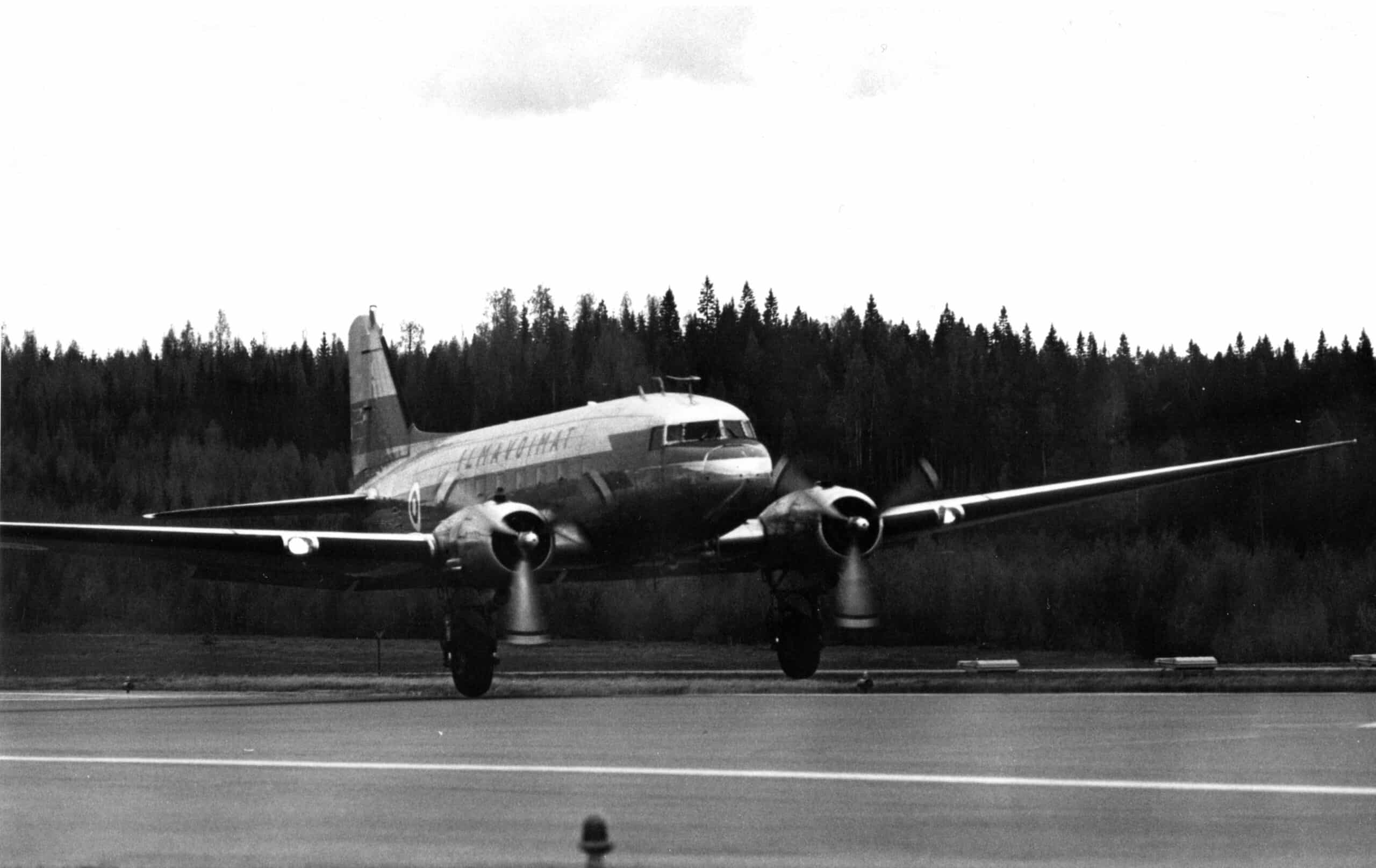 Mustavalkoinen kuva DC-3-koneesta laskeutumassa lentokentälle.