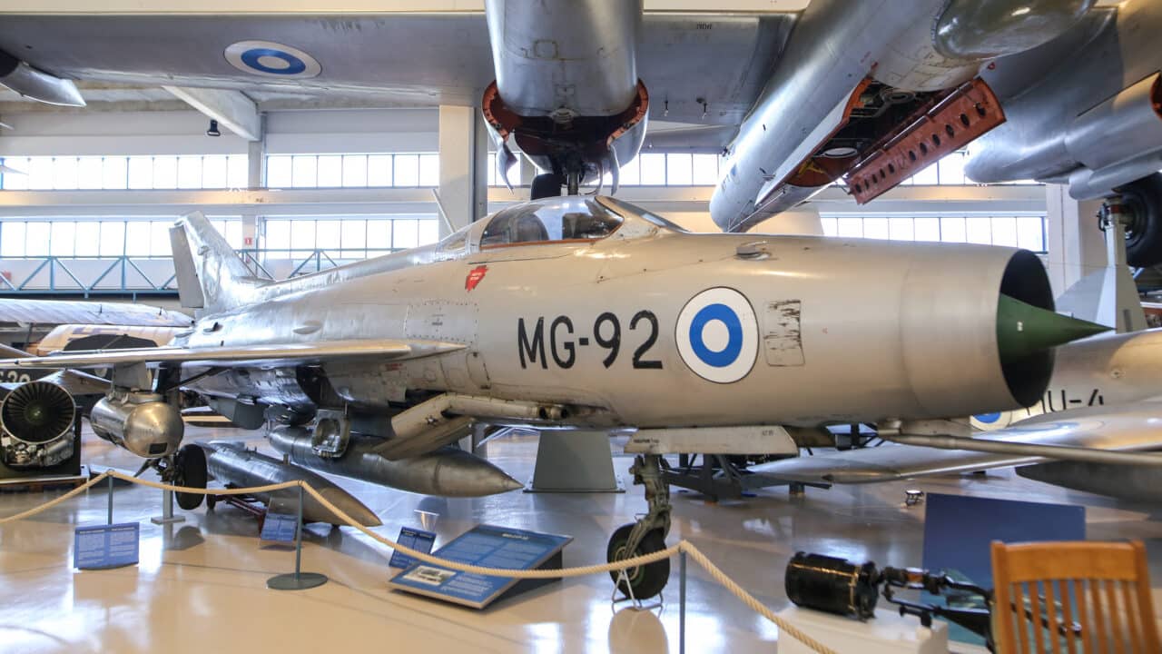 MiG-21F-kone näyttelyhallissa. Kone on hopeanharmaa, ja sen kyljessä on musta merkintä MG-92. Vieressä on sinivalkoinen pyöreä kokardi, Suomen kansallistunnus.