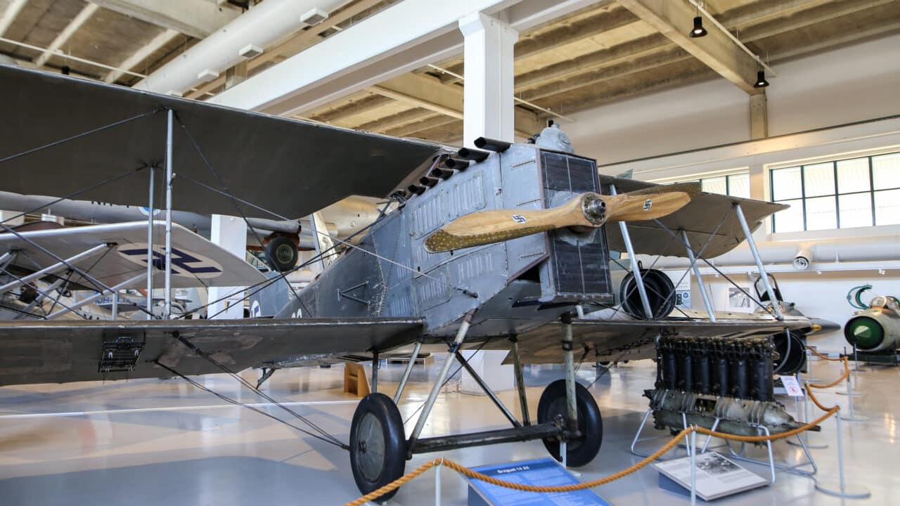 Kaksitasoinen, harmaa, puupotkurilla varustettu Breguet-lentokone näyttelyhallissa.